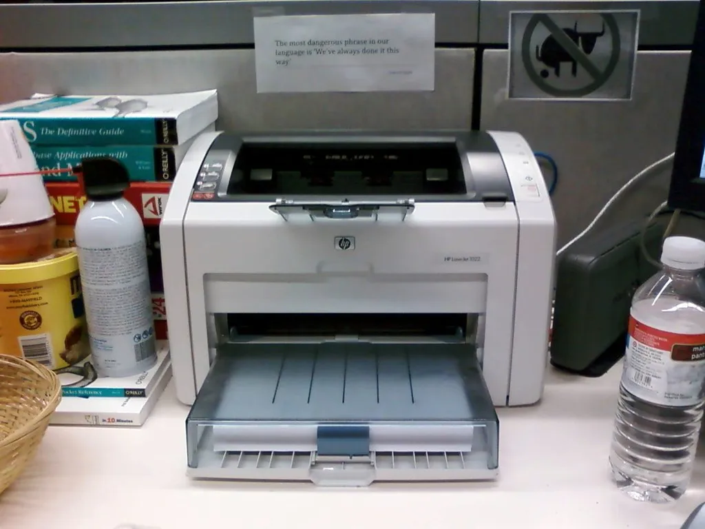 HP LaserJet printer in office showing paper tray and toner compartment